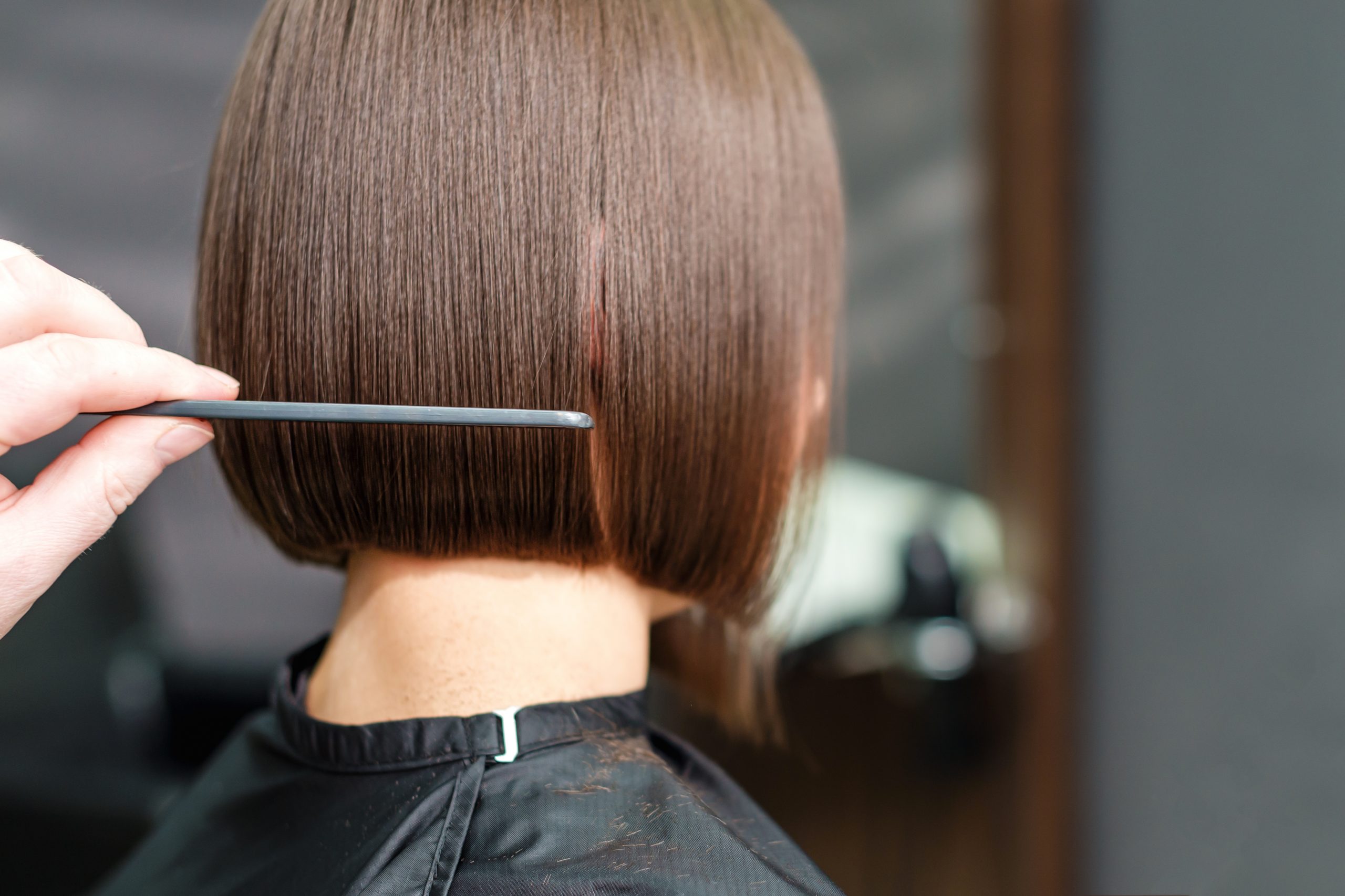 Hand Of Hairdresser Is Combing A Client's Short Brown Hair With A Comb. Salon Mayen Neustraße